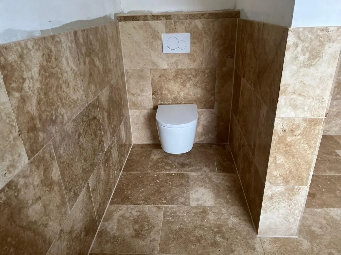 Wand-WC vor Naturstein-Wandfliesen in Travertin-Optik